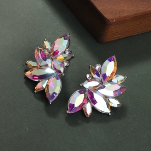 Macro shot of silver leaf earrings with shimmering rainbow AB crystals on wooden decor