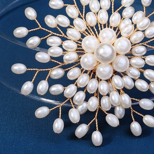 Gros plan d'une broche florale faite main avec perles blanches et fils dorés