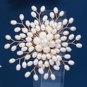 Détail d'une broche fleur en fil doré et perles blanches faite à la main pour robe