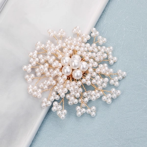 Gros plan sur une broche fleurie faite main en perles blanches et fil doré élégant