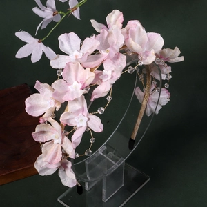 Détail d'un serre-tête fleurs en soie rose avec perles de cristal et fil doré sur fond sombre