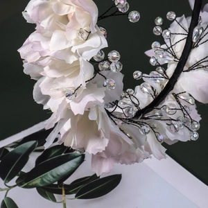 Détail de fleurs en tissu rose et blanc avec perles de cristal sur un serre-tête