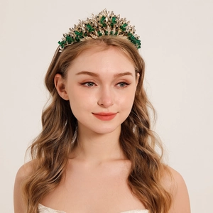 Détail d'une couronne de mariée luxueuse en or avec pierres vert émeraude et cristaux