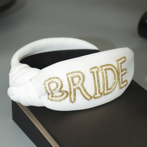 Detail of white bridal headband featuring handcrafted golden bead BRIDE lettering
