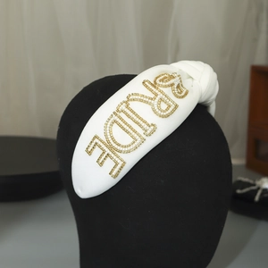 Close-up of handmade beaded BRIDE lettering on white satin knotted bridal headband