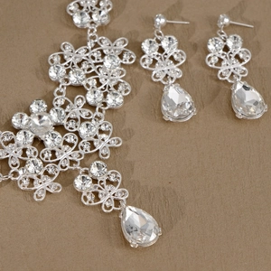 Macro shot of silver bridal jewelry set featuring floral rhinestones and teardrop crystals
