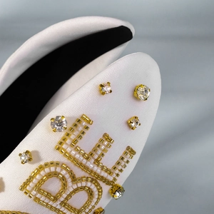 Detailed close-up of white bridal headband featuring hand-sewn beads and rhinestones