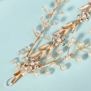 Détail de serre-tête fait main avec feuilles dorées, perles et cristaux sur fond bleu