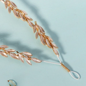 Detail shot of golden leaf crown with intricate leaf veins and white vine band design