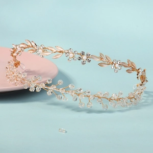 Close-up of handmade bridal headband with gold leaves, pearls and faceted crystals