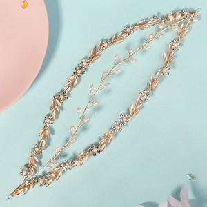 Close-up of golden bridal hair vine with white pearls, metal leaves and crystals