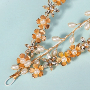 Detail of golden floral headband featuring white pearls and sparkling crystal stars
