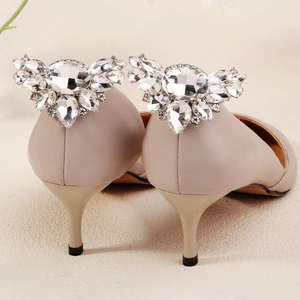 Vue macro d'une boucle en strass cristal en forme d'aile sur des talons hauts beiges