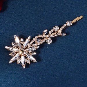 Elegant gold flower hair clip with sparkling rhinestones on a dark textured background