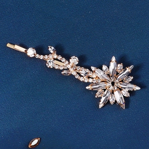 Close-up of sparkling floral rhinestone hair clip on deep blue textured background