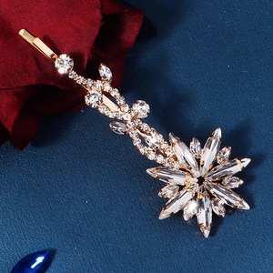 Close-up of golden floral hair clip with clear crystals on dark blue background