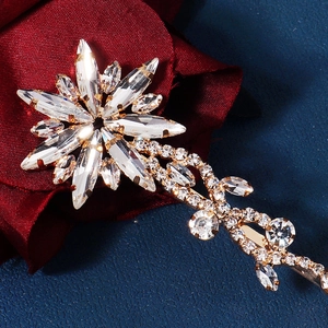 Detailed shot of starburst crystal hair clip on red silk rose with golden rhinestones