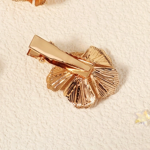 Detailaufnahme der goldenen Metall-Blumen-Haarklammer mit feiner Blütenblatt-Textur