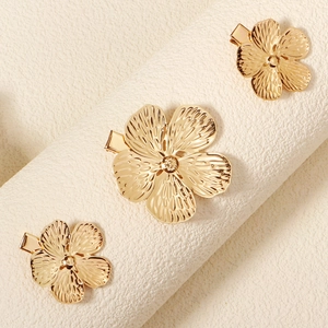 Nahaufnahme goldener Blumen-Haarspangen-Set mit feiner Textur auf mattem Sockel