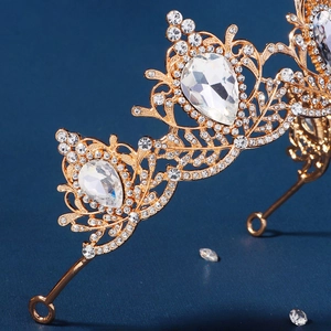 Close-up of golden Baroque crown with teardrop crystals and intricate hollow carving