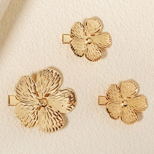 Detailansicht von drei goldenen Blumen-Haarspangen mit strukturierten Blütenblättern aus Legierung