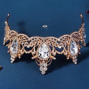 Detail view of gold baroque crown featuring intricate filigree and sparkling teardrop crystals