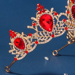 Close-up of golden baroque crown with intricate filigree and red teardrop gemstones