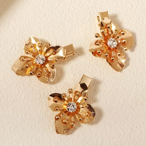 Detail von drei goldenen Blumen-Haarspangen mit strukturierten Blüten und Kristallen