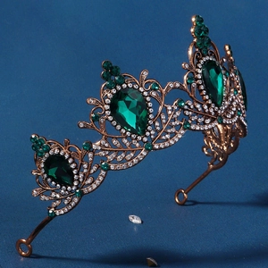 Macro detail of baroque bridal crown featuring emerald green gems and bronze metalwork