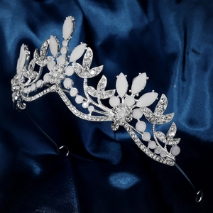 Elegant silver bridal crown with white rhinestones on luxury blue silk fabric