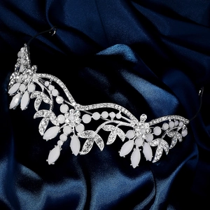Close-up of silver bridal tiara with sparkling rhinestones on dark blue satin fabric