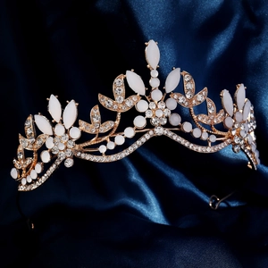 Detailed close-up of golden bridal crown with white rhinestones on blue silk