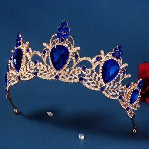 Detailed close-up of golden baroque tiara with large blue teardrop crystals and rhinestones