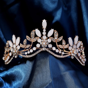 Close-up of golden bridal crown with white rhinestones on dark blue satin fabric