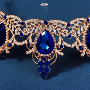 Macro shot of gold bridal crown featuring teardrop blue crystal and intricate leaf textures