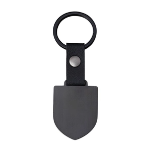 Detail of matte black dog tag keychain with textured leather strap and metal ring