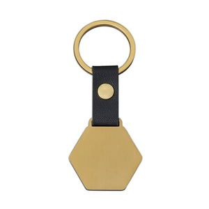 Detail of hexagon metal pendant and black leather strap on a golden keychain