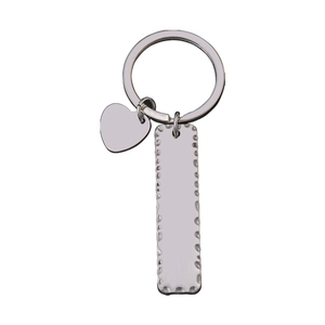 Détail d'un porte-clés en métal argenté avec cœur et plaque rectangulaire à bords ondulés