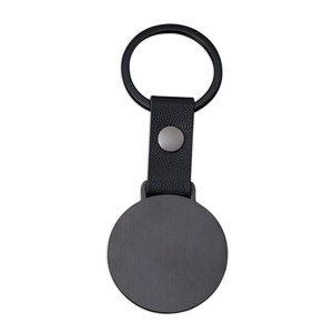 Detail of minimalist black metal keyring with lychee texture leather strap and round dog tag