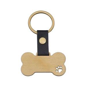 Detailed view of bone-shaped gold metal tag with paw cutout and black leather strap