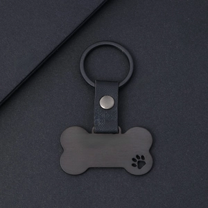 Premium black bone-shaped metal keychain with leather strap and hollowed paw print design