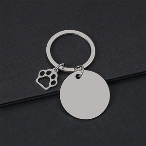 Macro detail of blank stainless steel round tag with hollow dog paw charm on black surface
