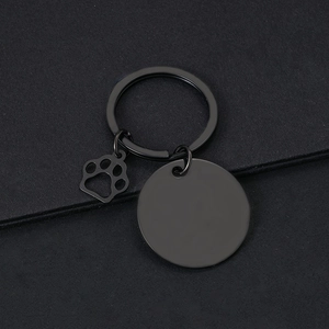 Close-up of black metal keychain with a blank round tag and hollow paw print charm