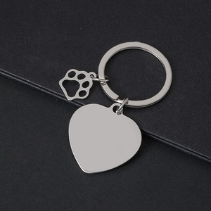 Polished silver heart-shaped metal keychain with paw charm on black textured background