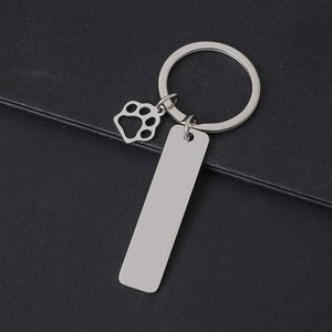 Close-up of silver stainless steel dog paw keychain with a rectangular engraving tag