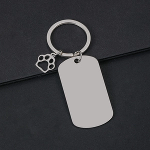 Detail of silver rectangle metal keychain with hollow paw print charm on black surface