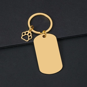 Golden metal dog tag keychain with hollow paw pendant on a premium black background