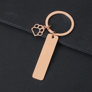 Rose gold metal keychain with a pet paw pendant and a rectangular blank tag for engraving