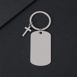 Llavero de cruz de metal plateado pulido con placa militar rectangular sobre fondo oscuro