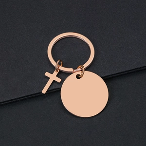 Llavero de cruz en oro rosa pulido con placa redonda grabable sobre un fondo negro